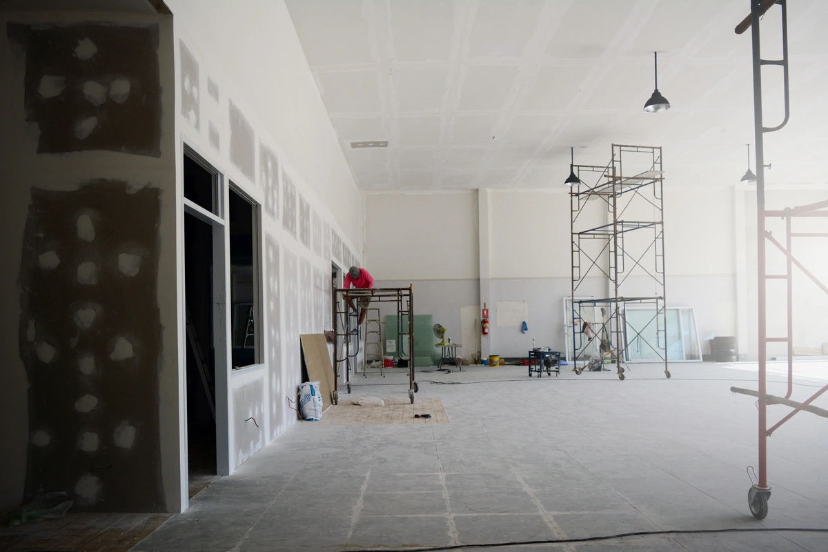 Grand chantier intérieur avec échafaudages et ouvriers préparant les murs pour la peinture, illustrant des projets de peinture et de rénovation commerciaux.